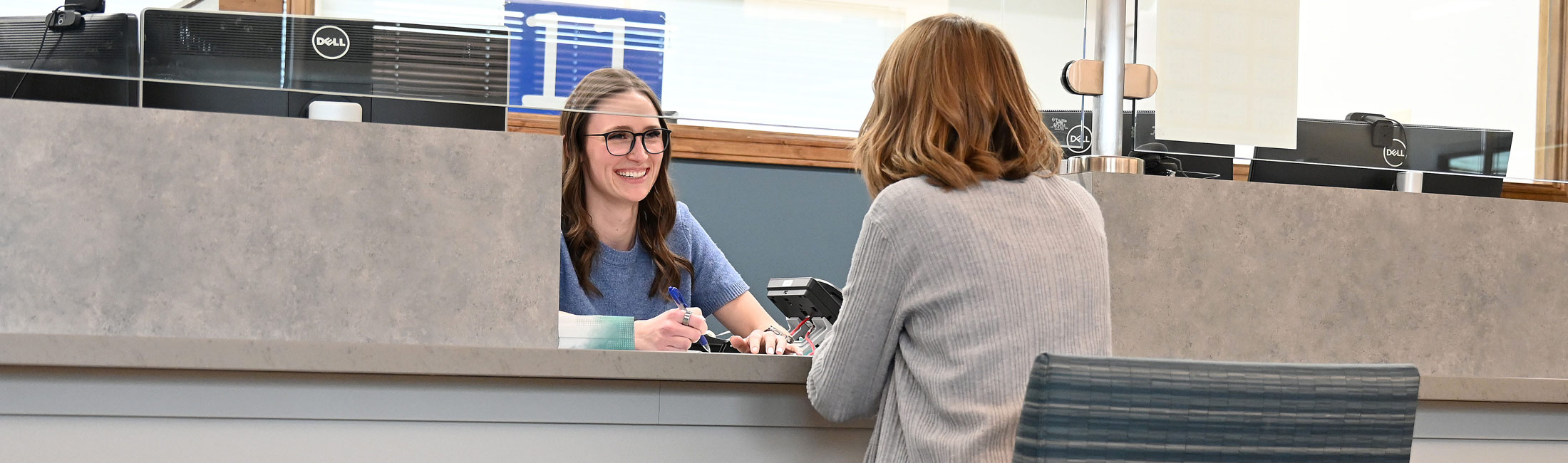 Woman seated assisting someone at service desk