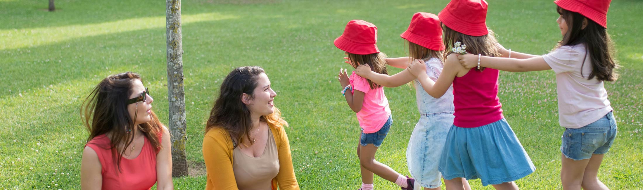 Children in red hats on grass