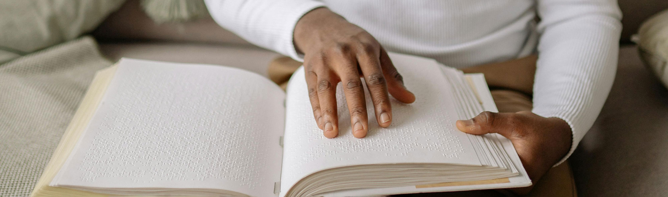 person reading a braille book with their hands
