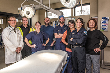 Group of hospital standing behind a gurney