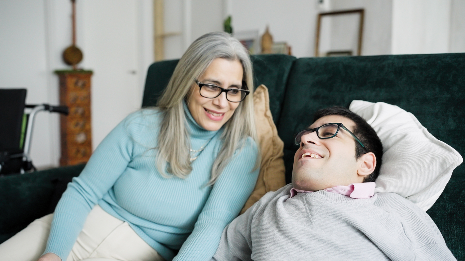 Woman sitting next to and smiling at her disabled son