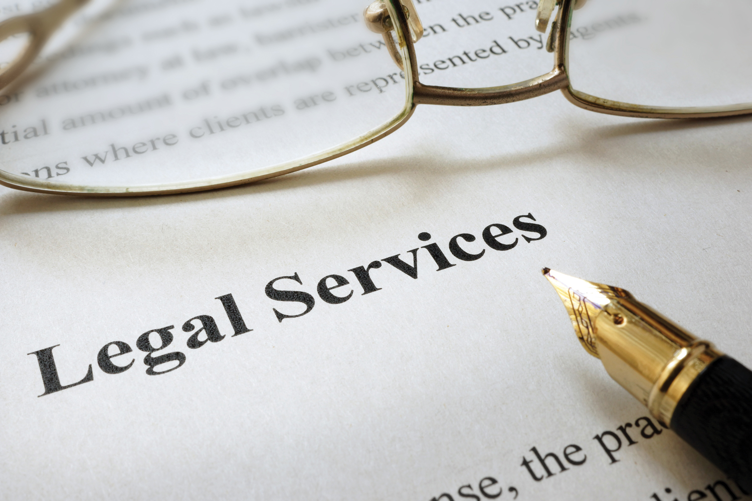 Legal Serivces typed on paper, on which sits a pair of reading glasses and a pen