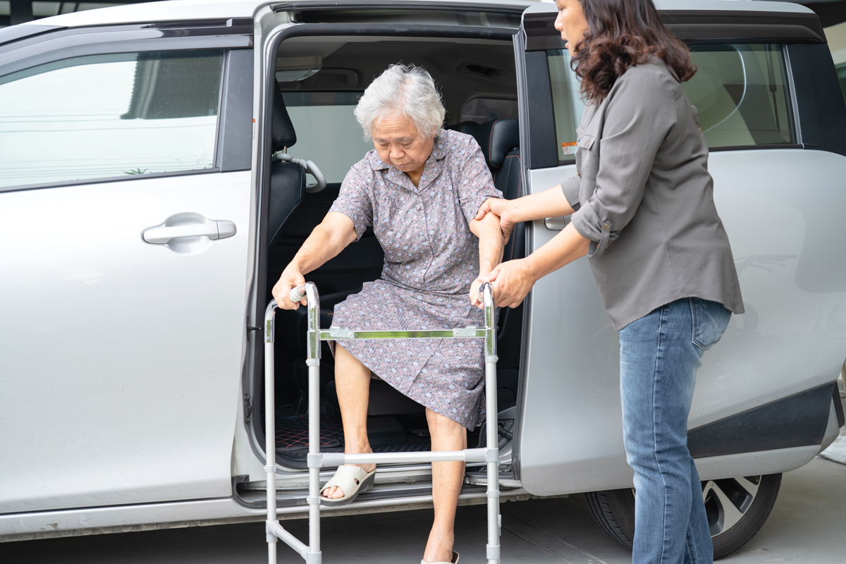Caregiver helping an elder lady out of her car